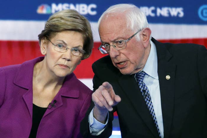 Elizabeth Warren and Bernie Sanders lean toward each other at a Democratic debate