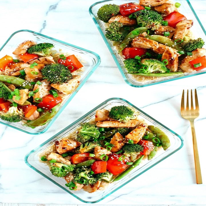 Three glass containers filled with sesame chicken and veggies.