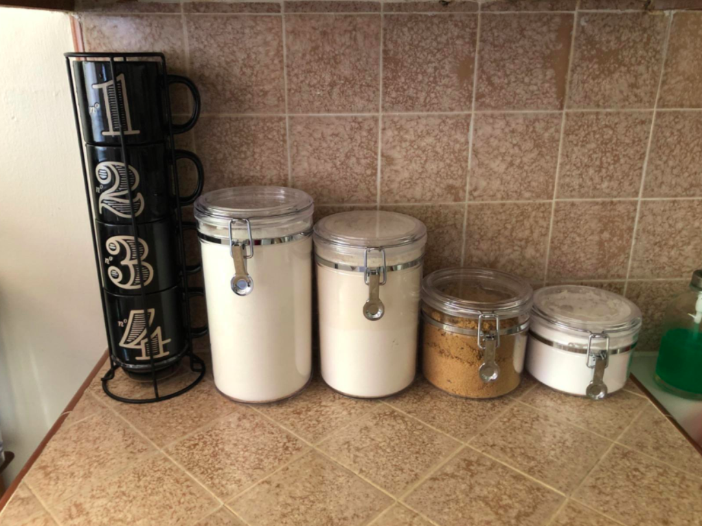the four canisters on the counter filled up with baking items 