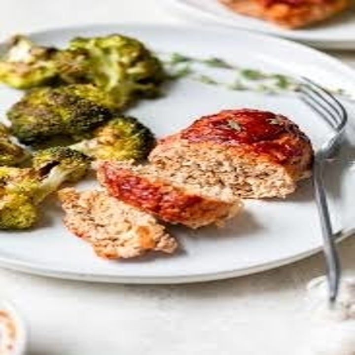A plate topped with an individual meatloaf and roasted broccoli.