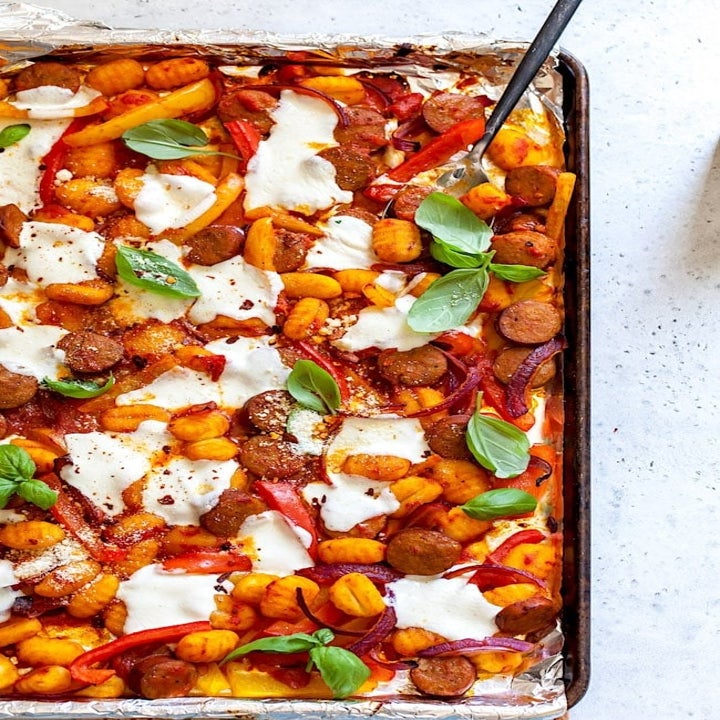 Gnocchi tossed in tomato sauce with sausage, mozzarella, and basil on a sheet pan.