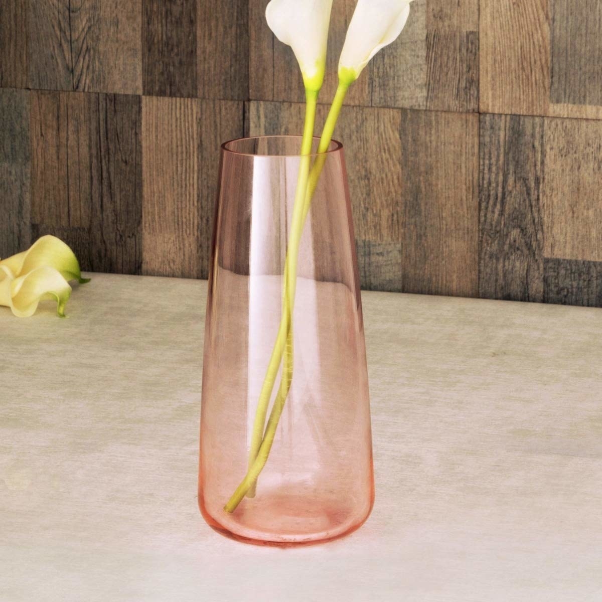 A pink glass vase with a flower in it