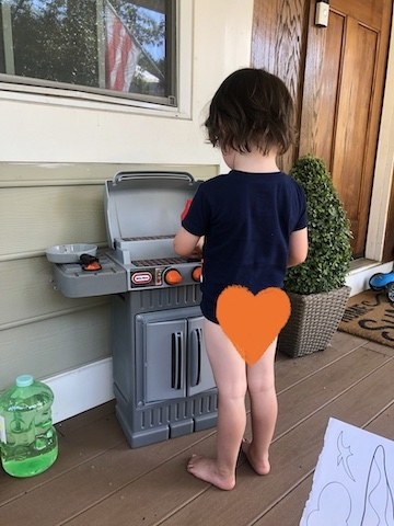 A toddler plays at his toy grill during the first day of potty training.