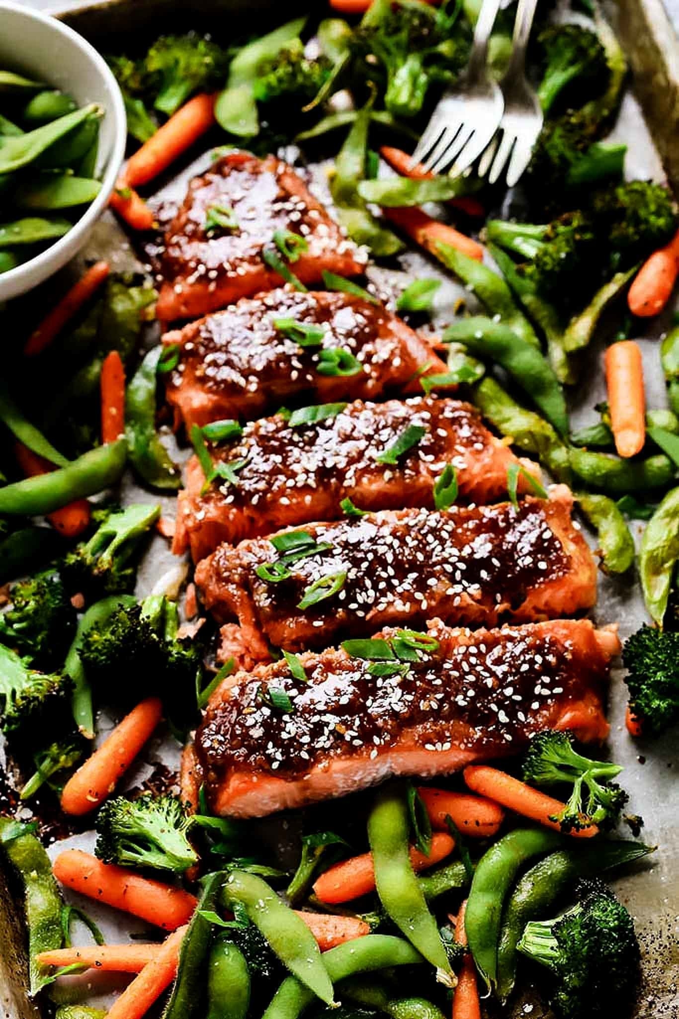 A sheet pan topped with glazed miso salmon, edamame, carrots, and broccoli.