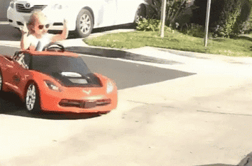 a GIF of a toddler looking cool in a toy car.