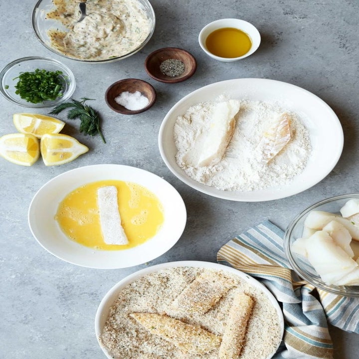 Preparing fish and chips by dredging fish into flour, eggs, and bread crumbs.