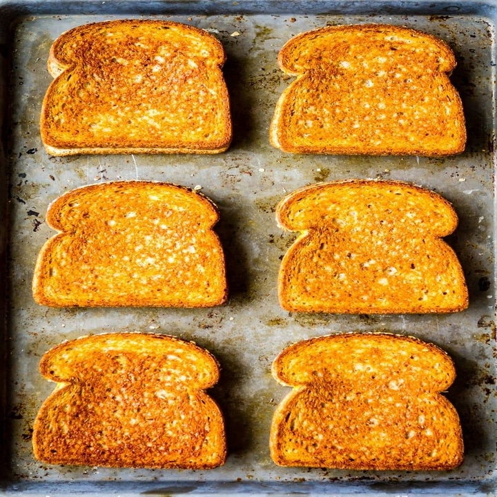 Six golden brown grilled cheese sandwiches on a sheet pan.