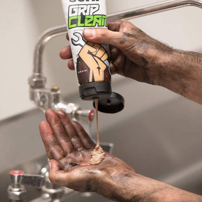 A person squeezing hand wash out of a tube on their dirty hands