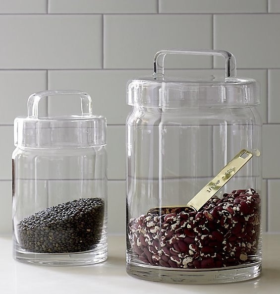 one large and one medium glass jar with glass lids full of dry rice and a scooper