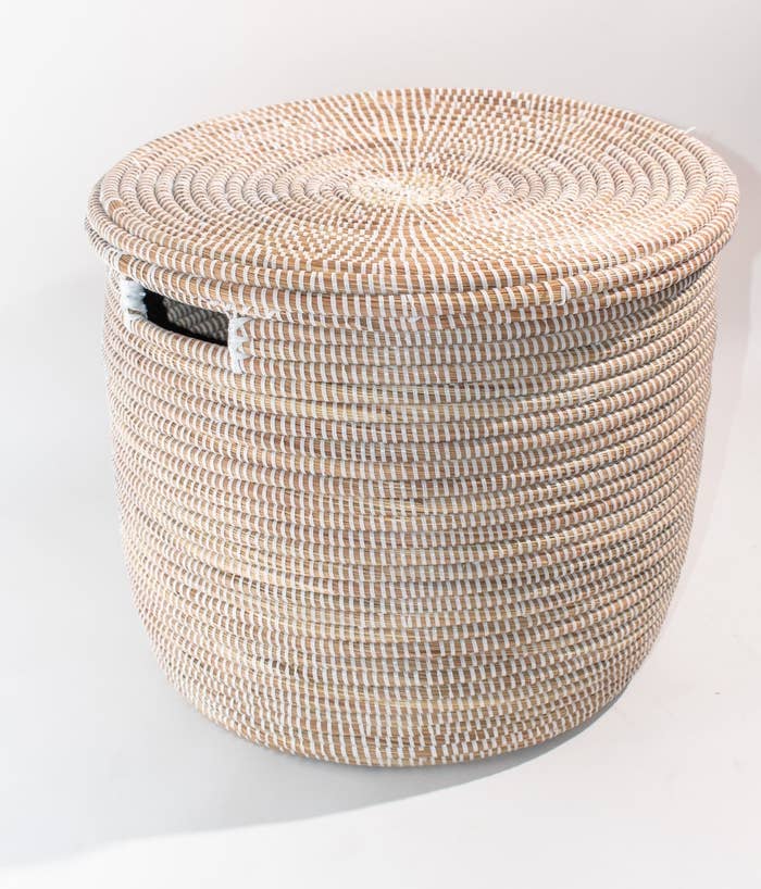 The tan basket with white thread and a rectangular hole on the side for handles with a matching lid