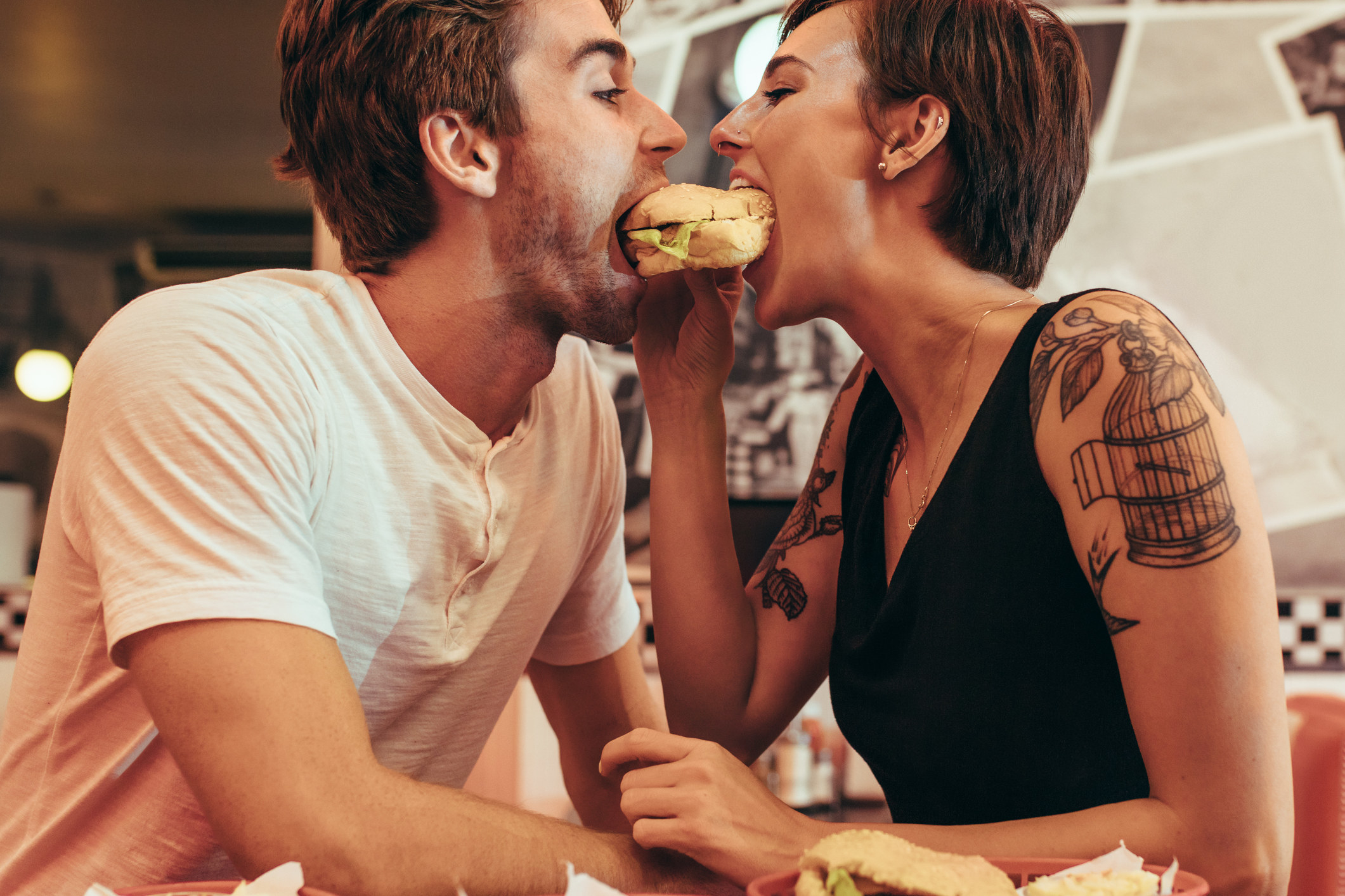 Un couple partageant un hamburger dans un restaurant.