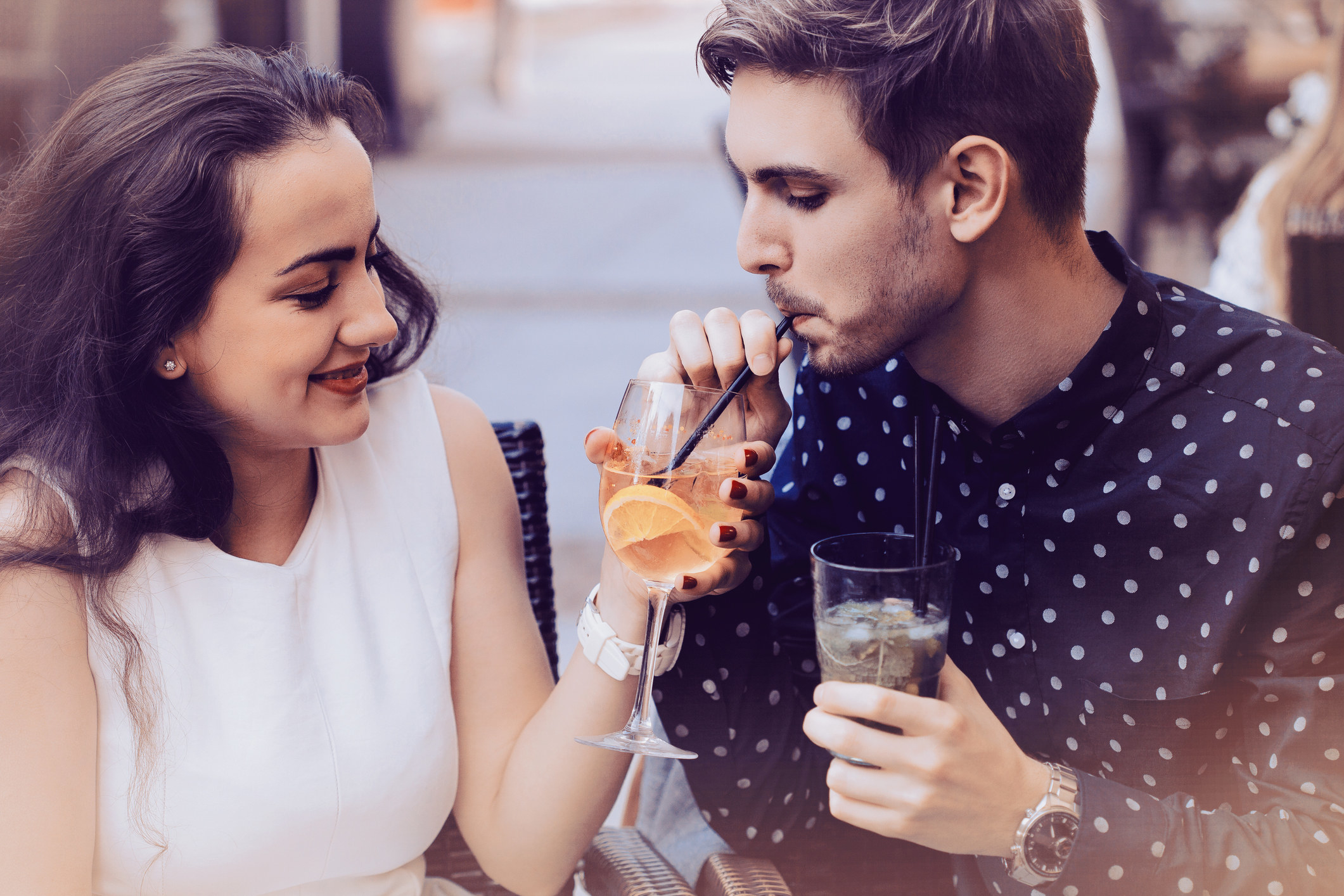 Une personne goûte le cocktail de son ami avec une paille.