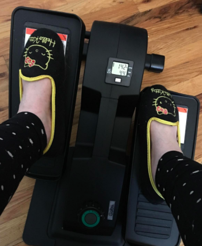 Reviewer uses small black elliptical while wearing Hello Kitty slippers
