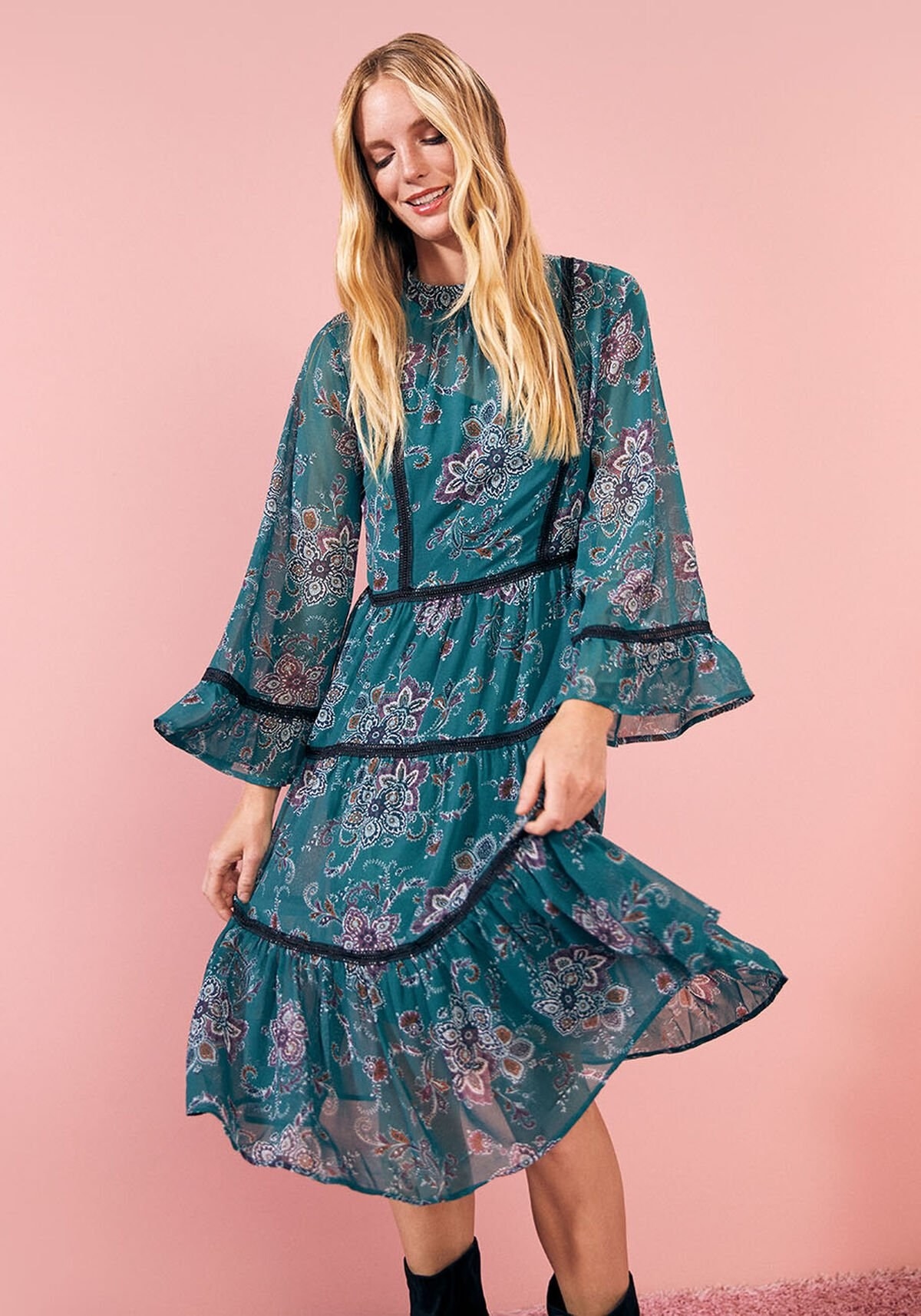 A model wears the loose midi dress with flowy bell sleeves and a tiered silhouette, made with green chiffon and a lace trim, that comes down to their knees