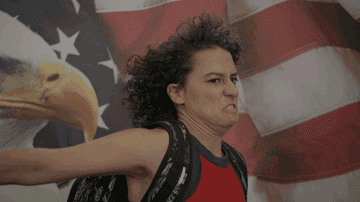 Ilana from Broad City giving an intense salute in front of an America flag background