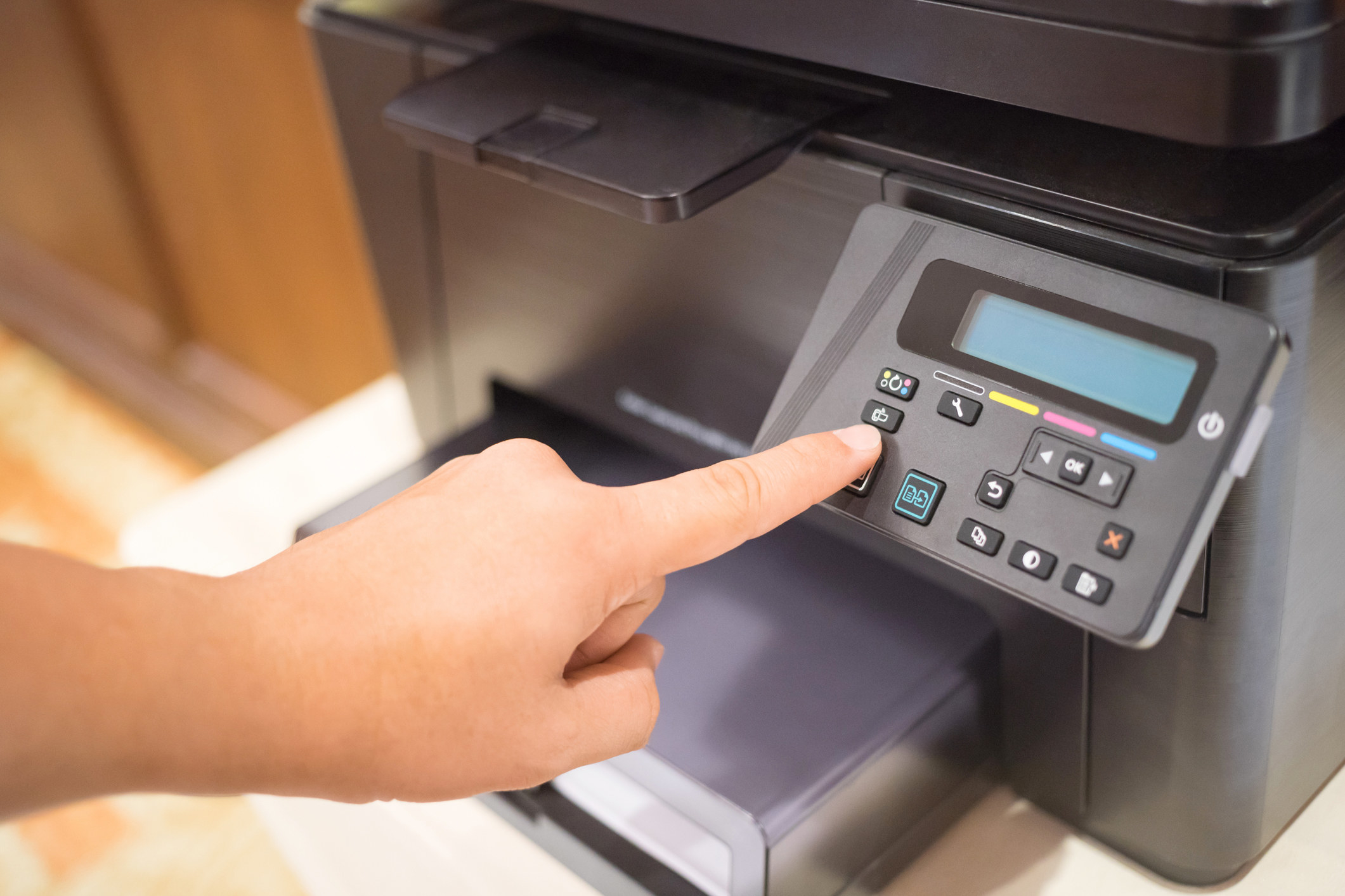 A photo of a finger pressing a button on a computer printer