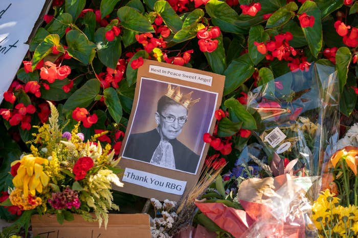A photo of Ginsburg wearing a crown with the words &quot;Thank You RBG&quot; on it rests amid flowers