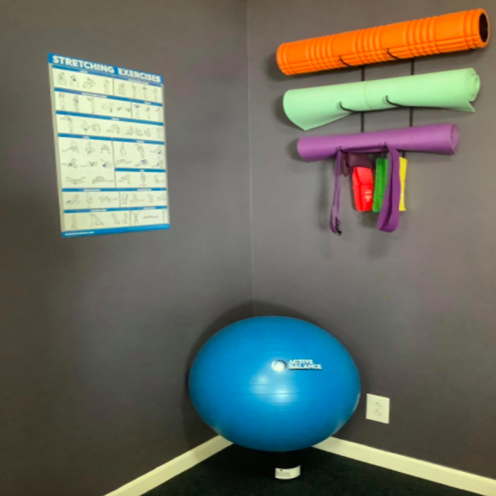 Reviewer hangs up red, green, and yellow yoga mats and resistance bands on home gym wall mount