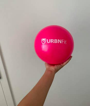 Reviewer holds mini pink pilates ball in their hand, showing the size is similar to a dodgeball