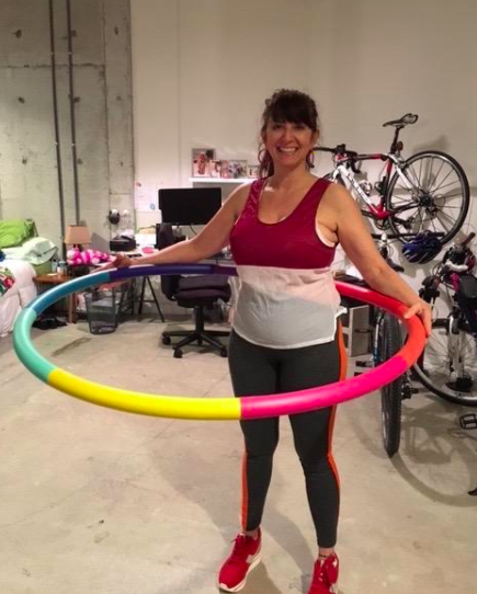 Reviewer uses rainbow-toned weighted sports hoop in their home garage