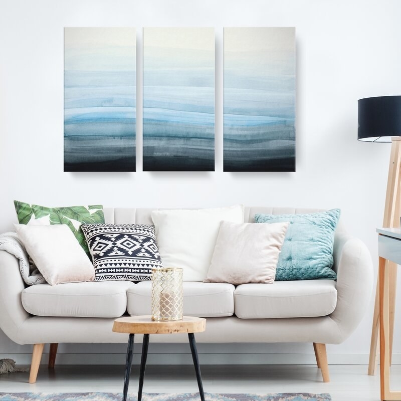 A painting sectioned into three canvases hanging in a living room 