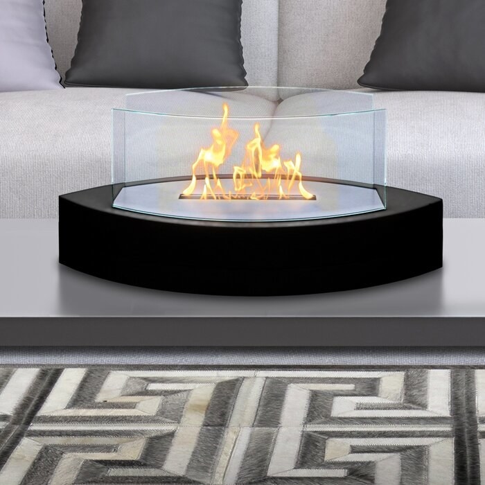 A propane tabletop fireplace with a black base in a living room.