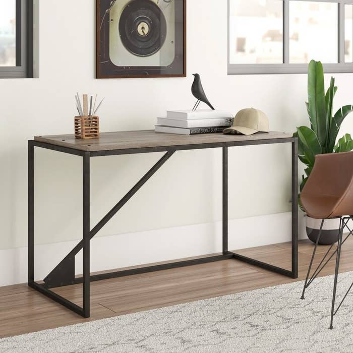Brown wood-top desk with dark brown metal base with a piece going diagonally across the middle back