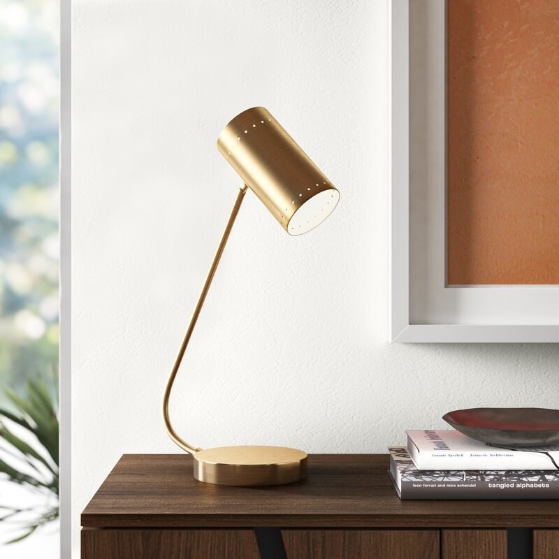 The gold metal desk lamp with a circular base and circular oval shade.