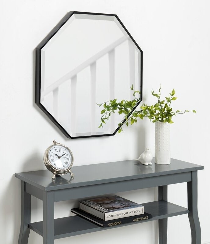 The octagon-shaped mirror with a black border above a console