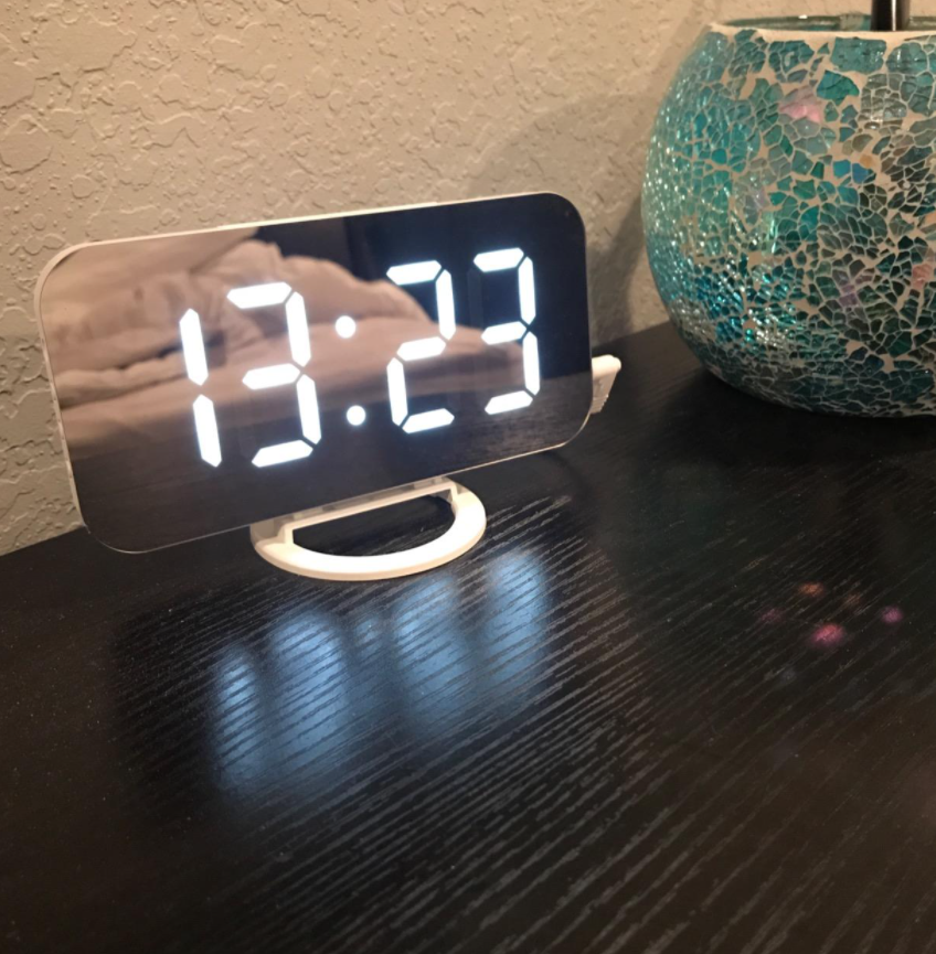 reviewer photo of digital alarm clock with a mirror surface that displays the time in large glowing numbers