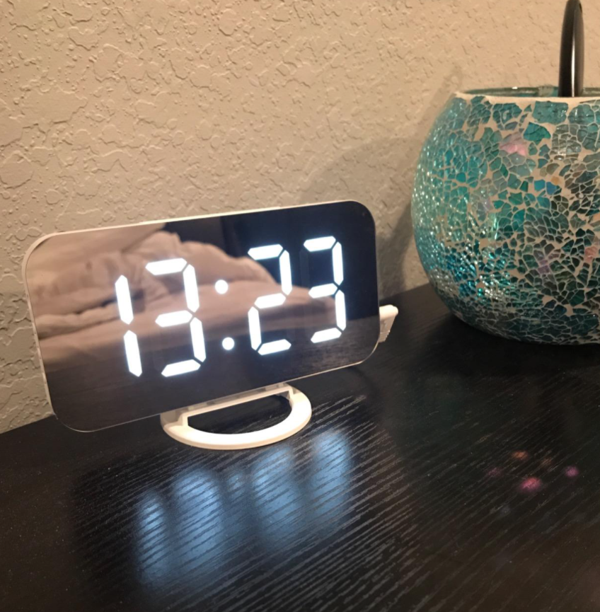 reviewer photo of digital alarm clock with a mirror surface that displays the time in large glowing numbers