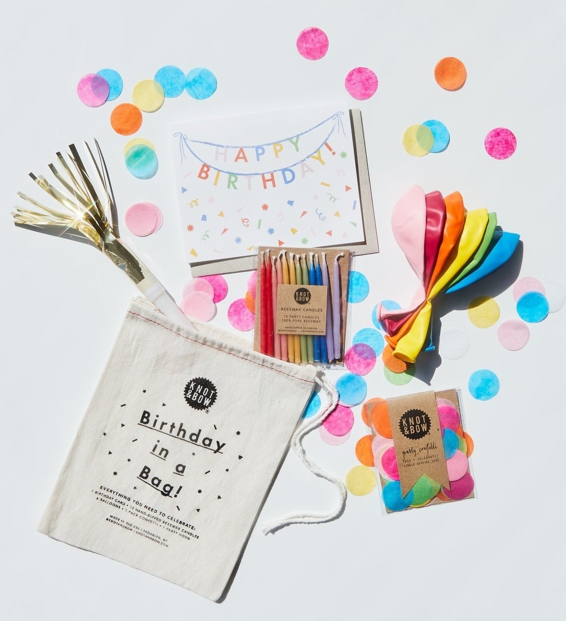 The various items that come with the birthday in a bag including the candles, balloons, card, confetti, and the bag