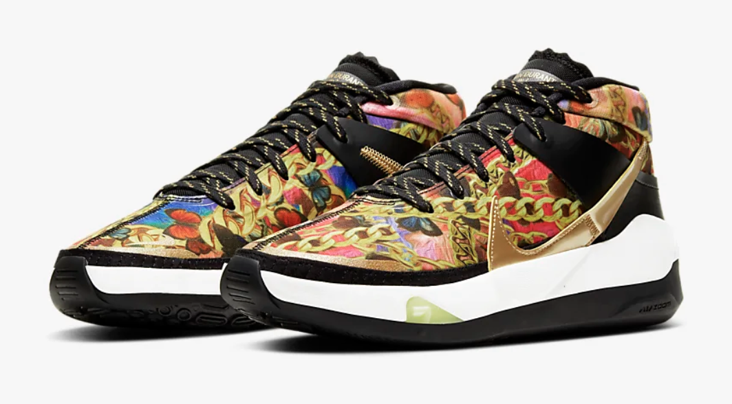 The sneaker features a multicolor print of butterflies and chains with gold and black details on the swish, sole, and laces 