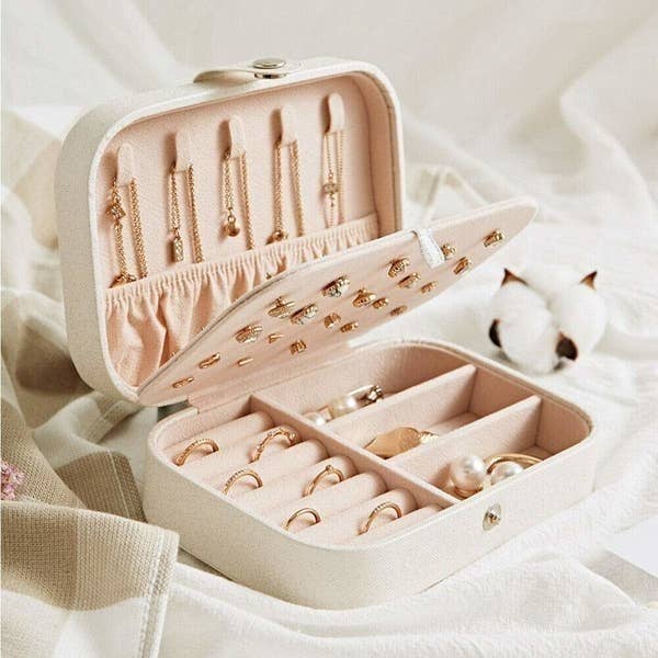 A pale pink storage box with jewellery in it