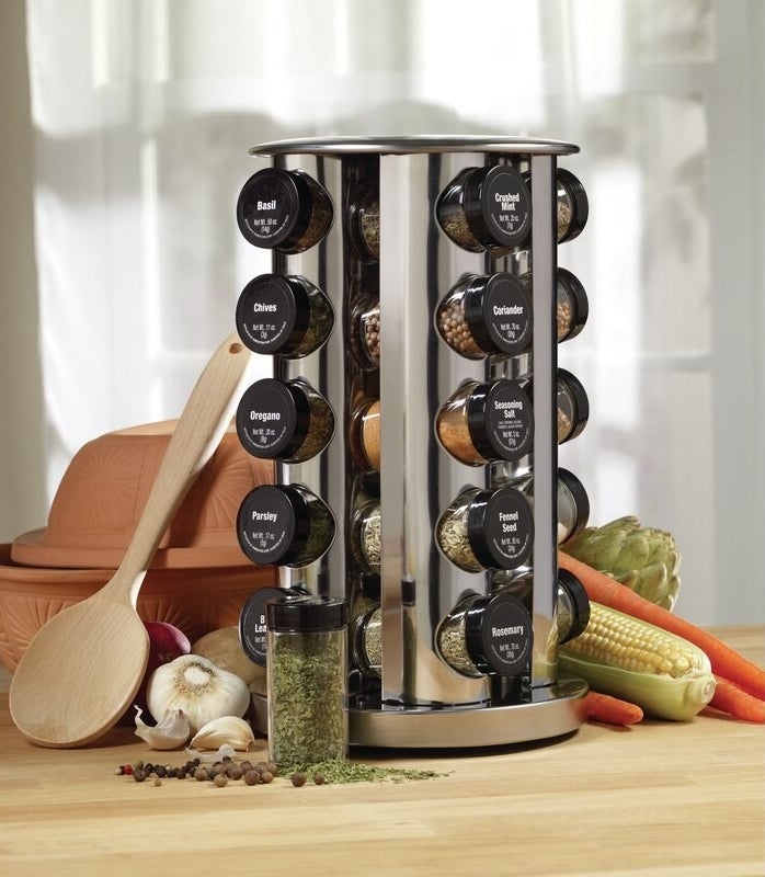 Stainless steel spice rack with jars and black lids with the labels on top