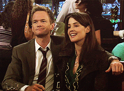 Barney and robin high fiving each other while sitting on the same side of a restaurant booth
