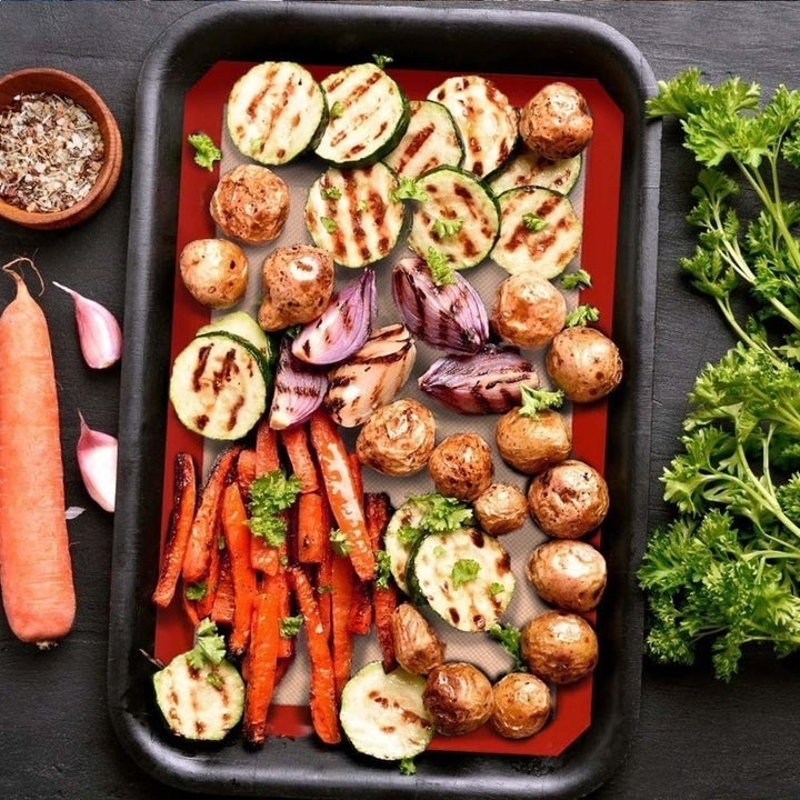 The silicone baking mat pictured with roasted veggies on it.