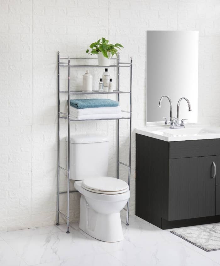 The bathroom storage unit being used to hold towels and toiletries.