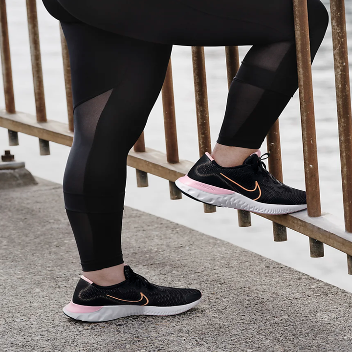 The sneakers in black with pink and orange details, on a model's feet 