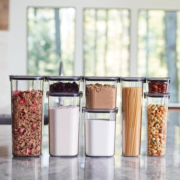 Several different sizes of containers filled with flour, cereal, pasta, and sugar