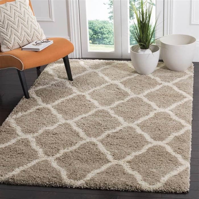 A taupe shaggy rug with diamond-shaped designs on it in white.