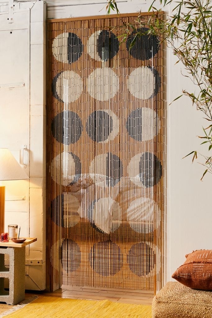 Beaded curtain with moon phase pattern dividing hallway from room 