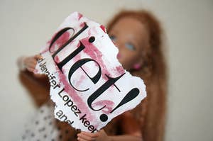 Barbie holding up a ripped newspaper headline saying 'diet!'