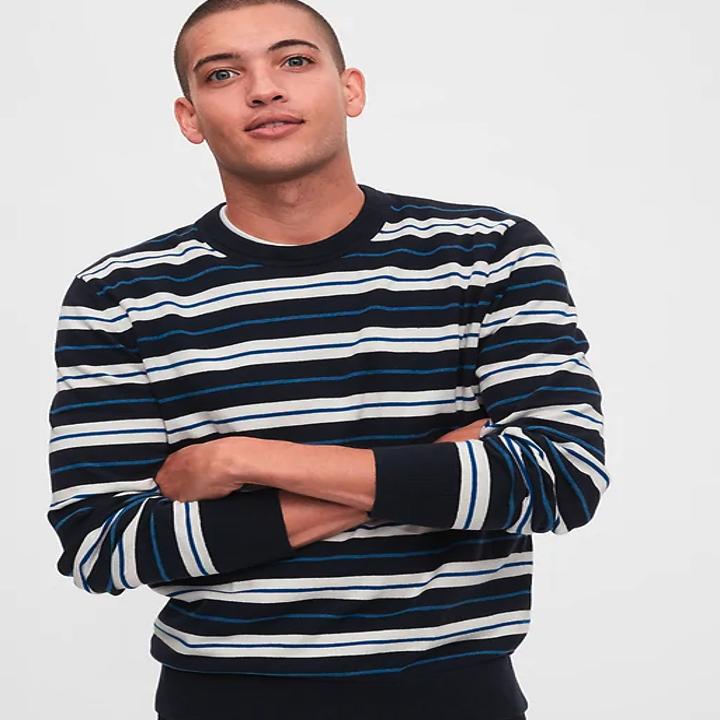 A male model wearing a white, black, and green striped sweater