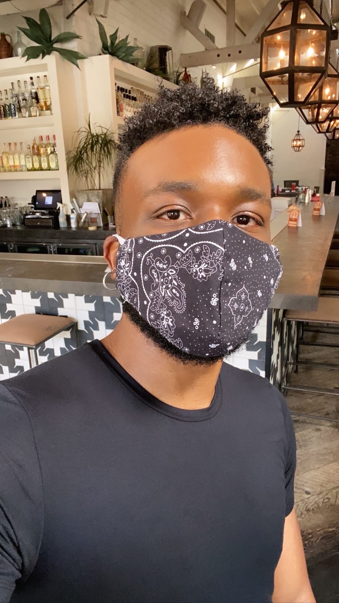 A person taking a selfie while wearing a simple paisley-print mask