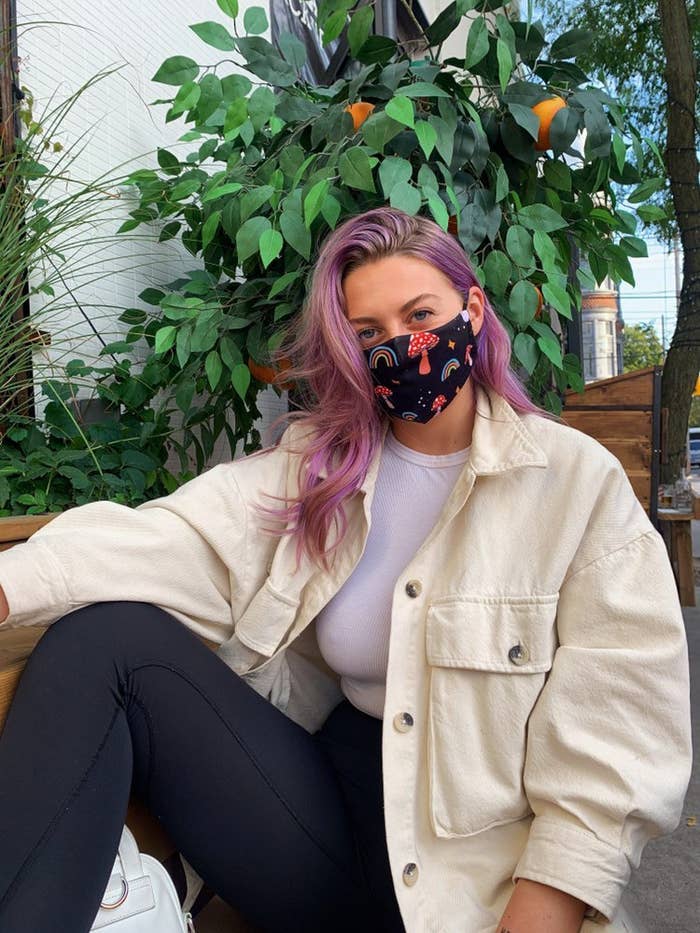 A pink-haired person wearing an oversized shacket and mushroom print face mask