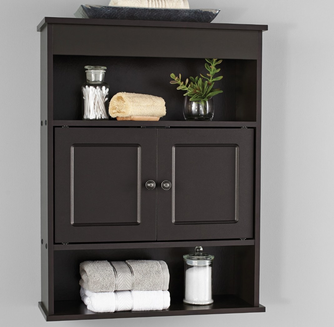 A bathroom cabinet holding towels, a loofa, and qtips