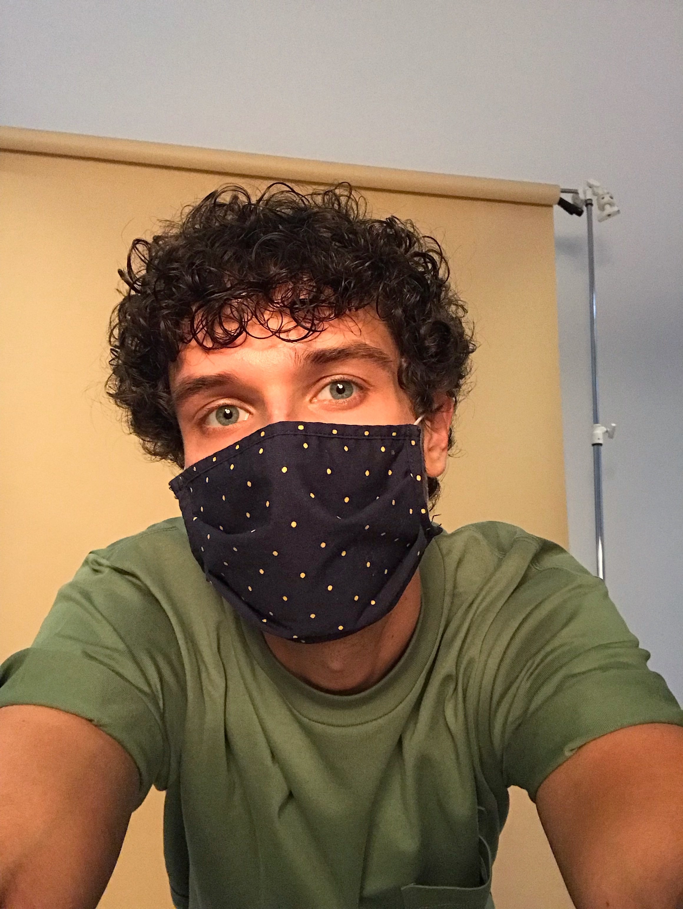 A person taking a selfie while wearing a polka dot print face mask
