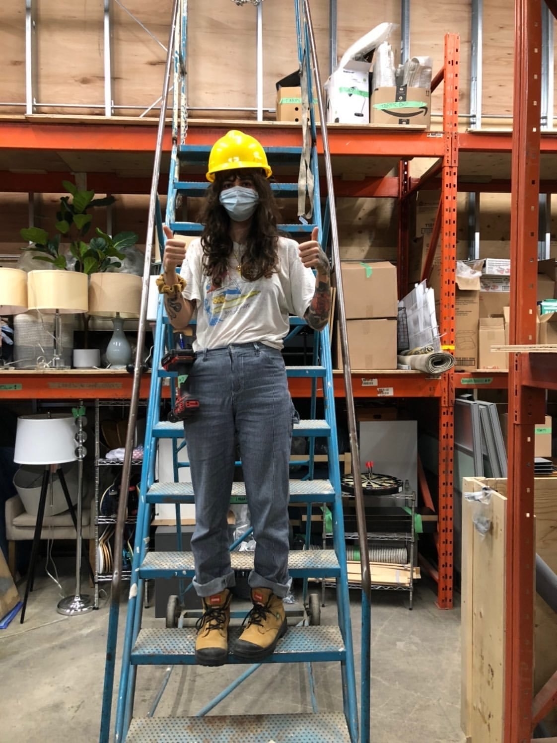 Someone standing on a ladder at a hardware store while wearing a disposal face mask