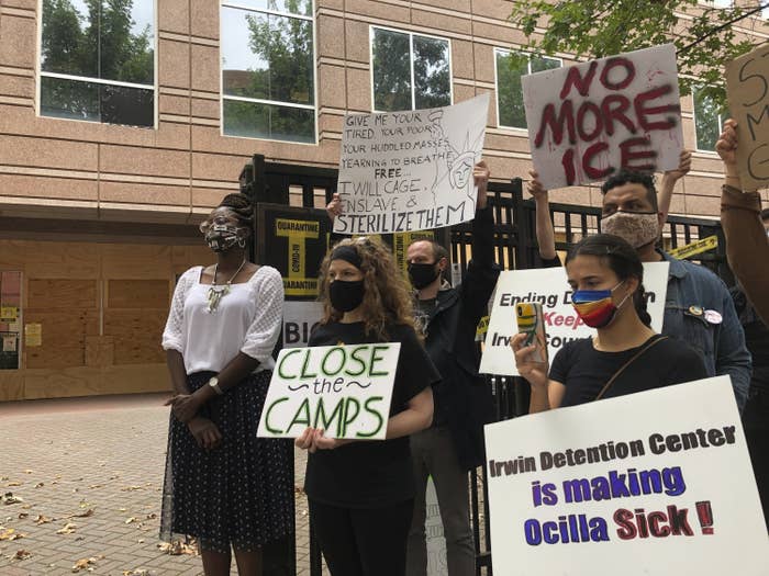 People wearing face masks stand outside, holding signs and protesting ICE and the Irwin County Detention Center